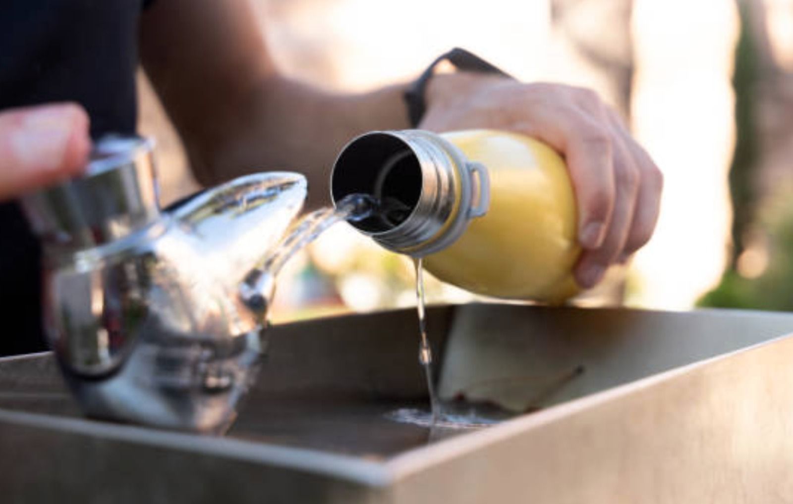 Una persona emplena una botella d'aigua en una font