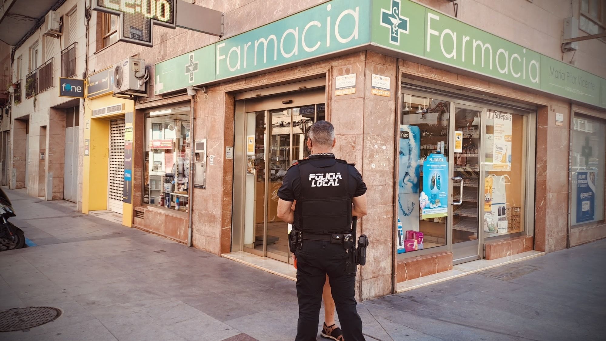 Un Policia Local de Elche junto a una farmacia