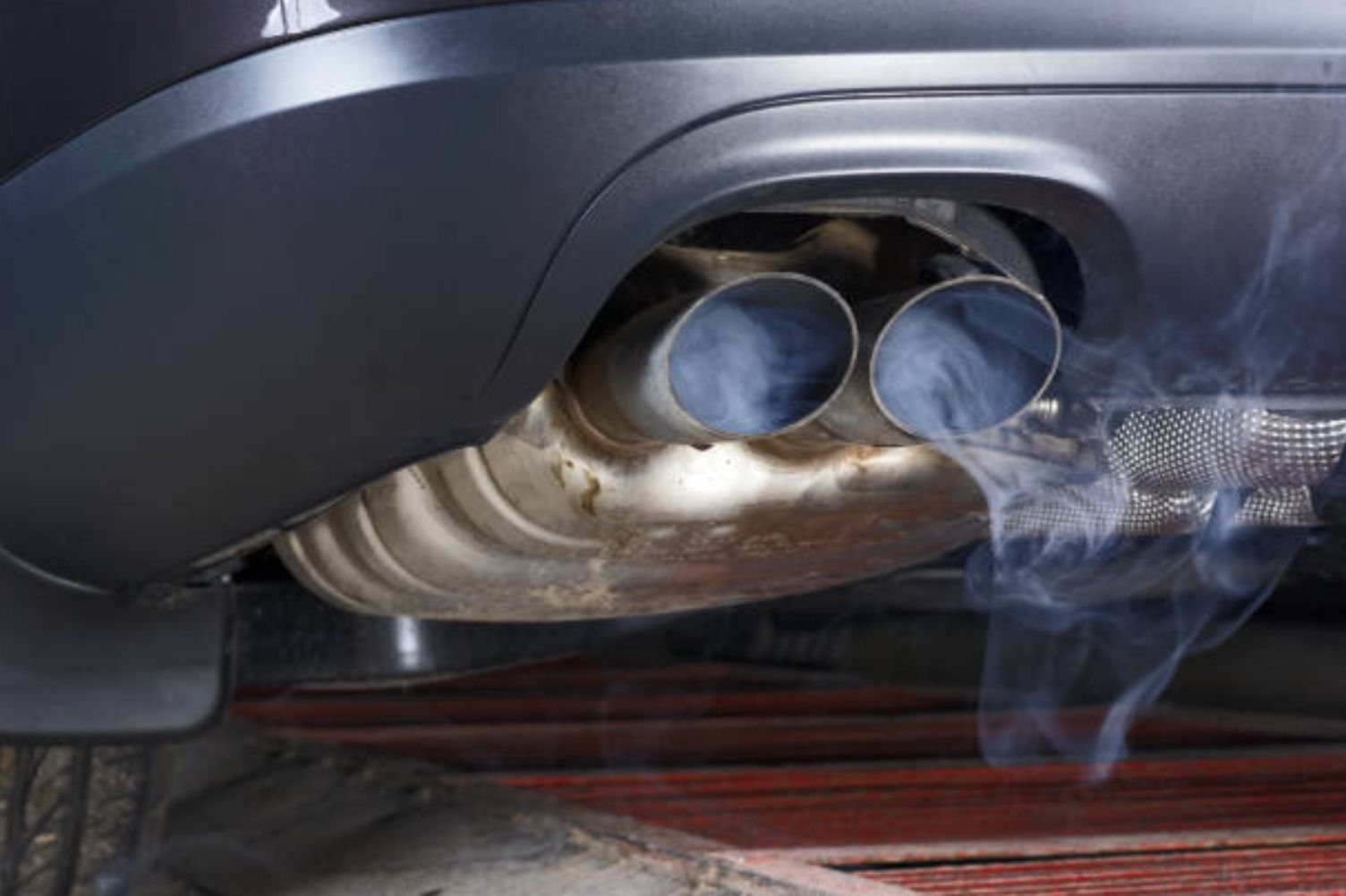 El tubo de escape de un coche emitiendo gases