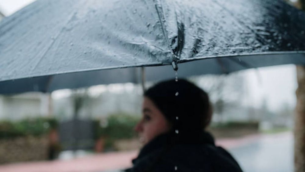 Una mujer sostiene un paraguas bajo la lluvia Una mujer sostiene un paraguas bajo la lluvia