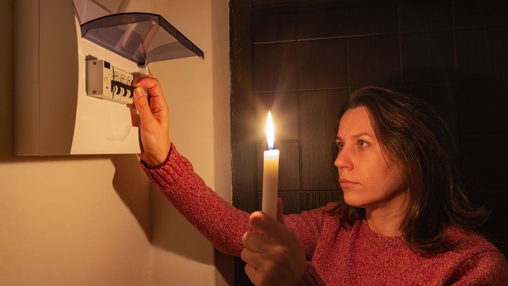 Una persona con una vela junto al cuadro de luz durante un apagón (Foto: Getty images)
