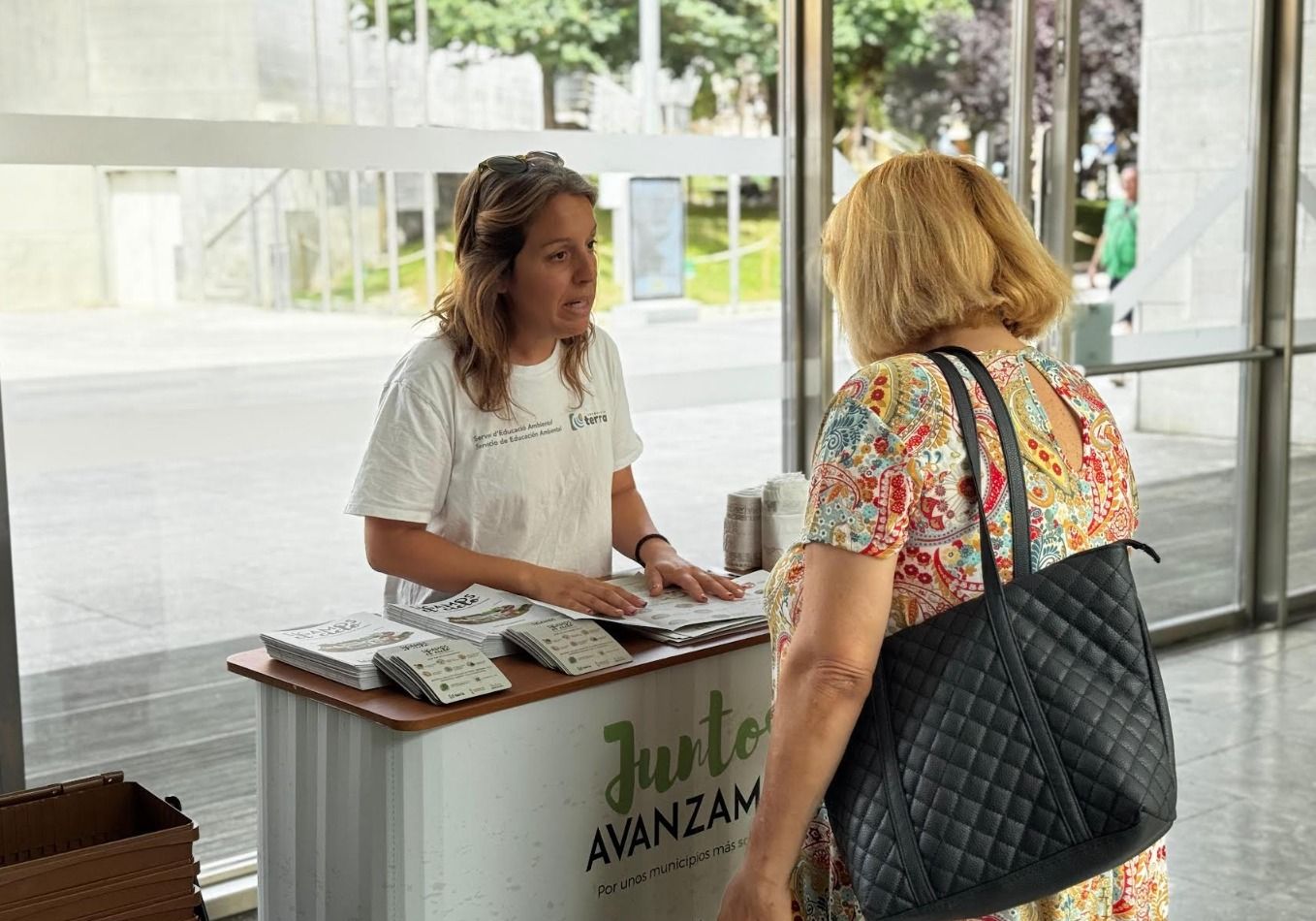 Una dona s'informa sobre l'ús correcte dels contenidors marrons a Sant Vicent