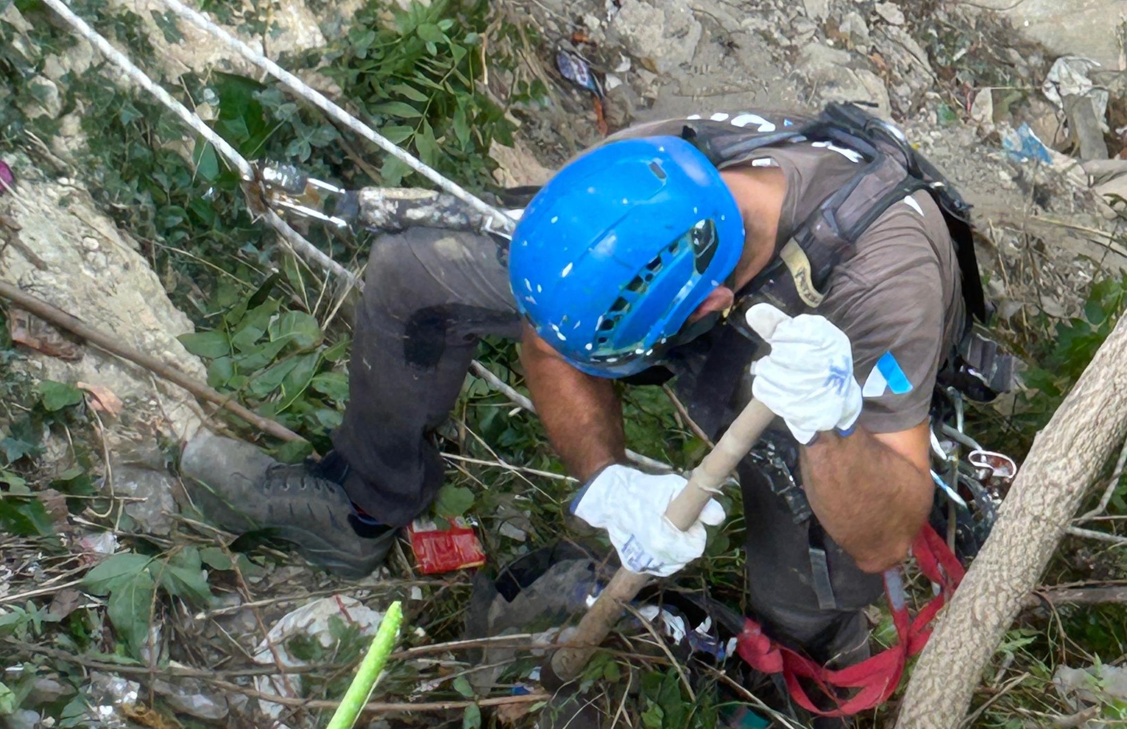 Un operario elimina basura debajo de un puente de Alcoy