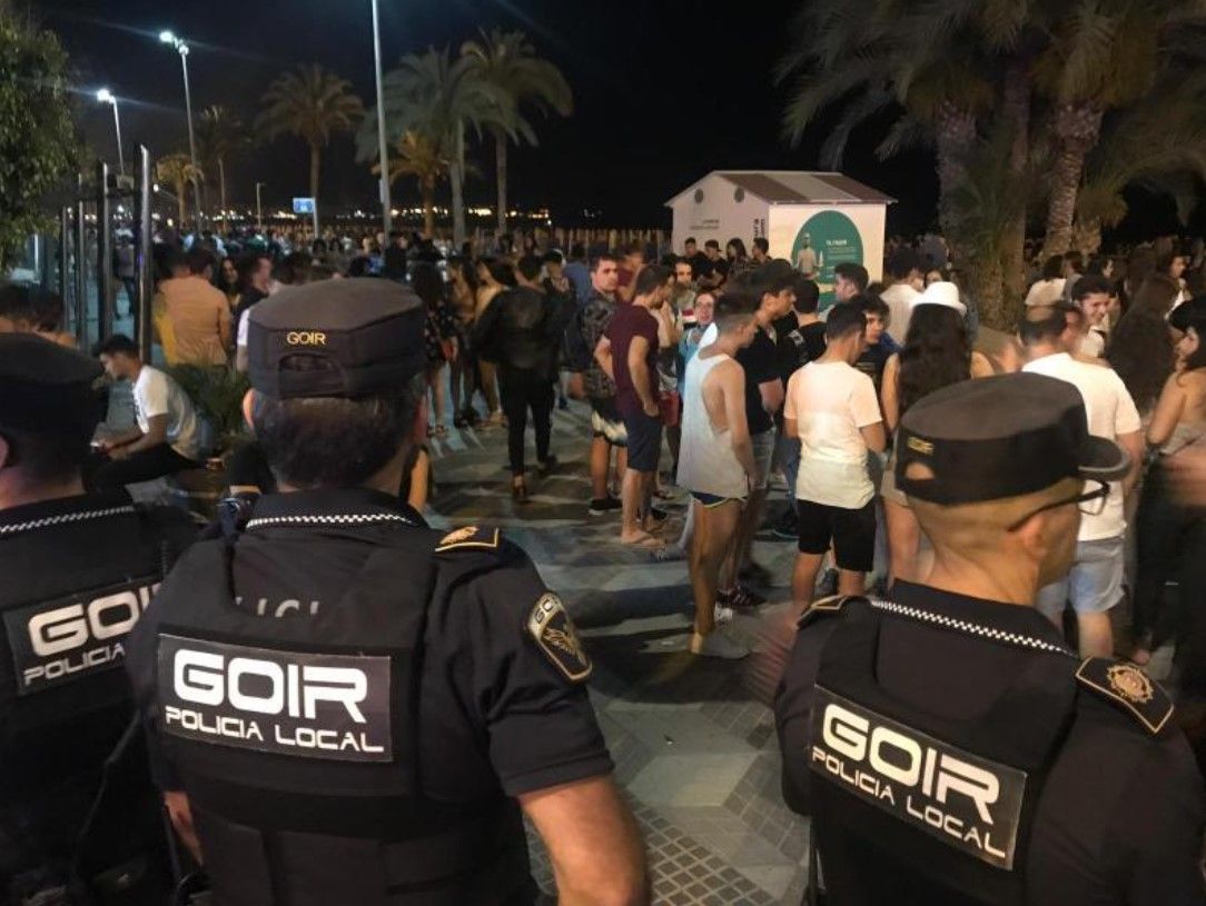 Agentes de la Policia Local junto a un grupo de jóvenes en El Postiguet durante las Hogueras