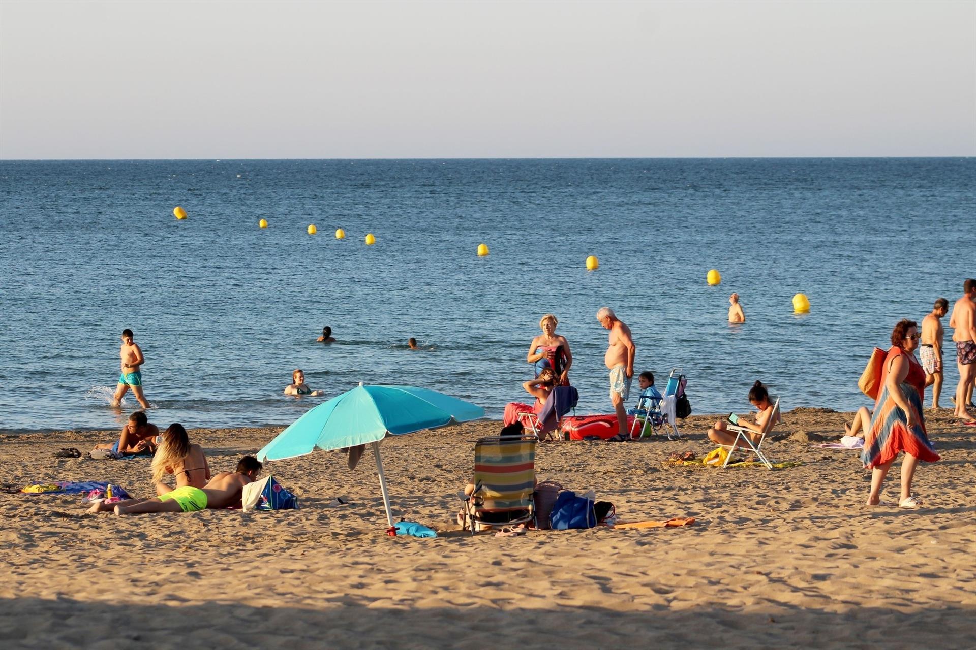 Diverses persones gaudixen en una platja de Dénia