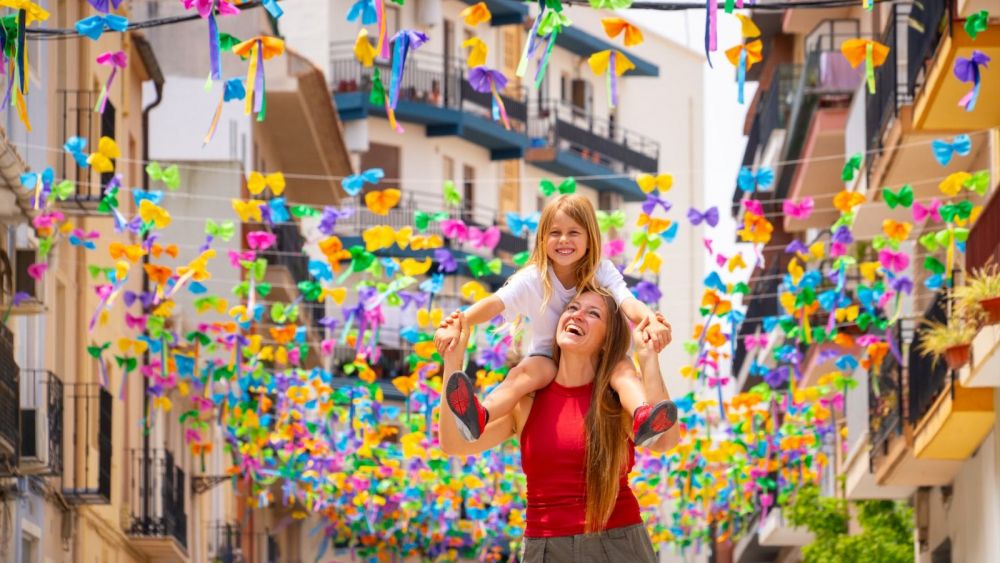 Una madre y su hija pasean pasean por un centro histórico de Benissa repleto banderolas de colores