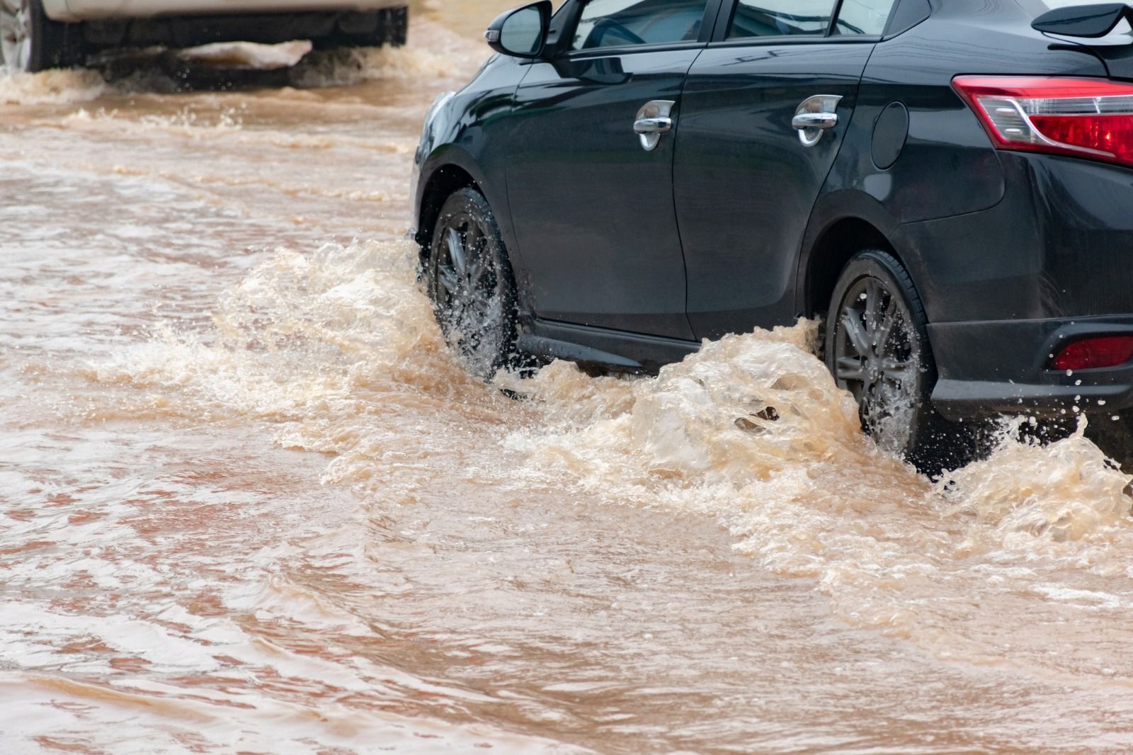 Un coche circula por una carretera llena de agua durante por la lluvia en Alicante