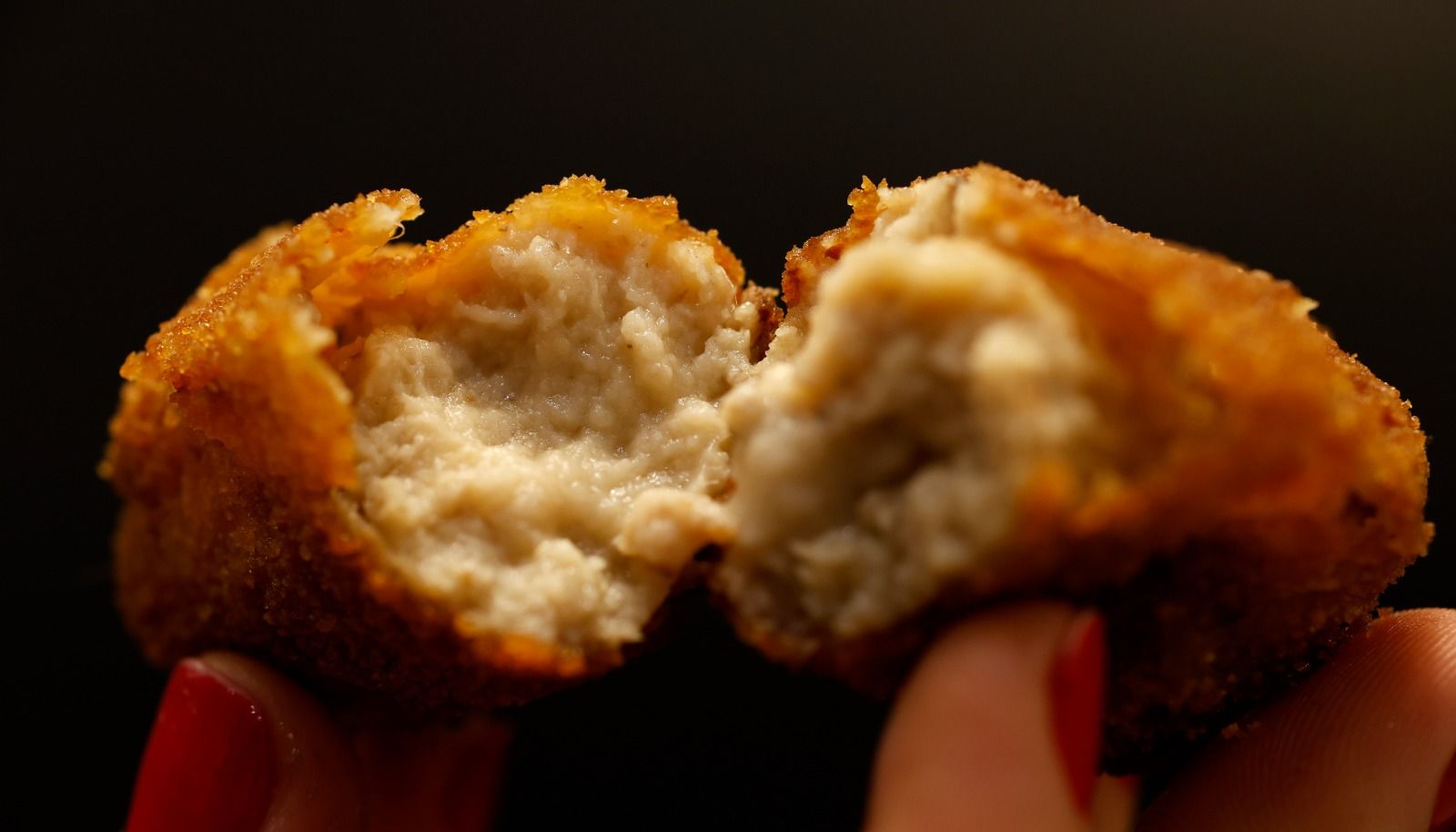 Una persona partiendo una croqueta