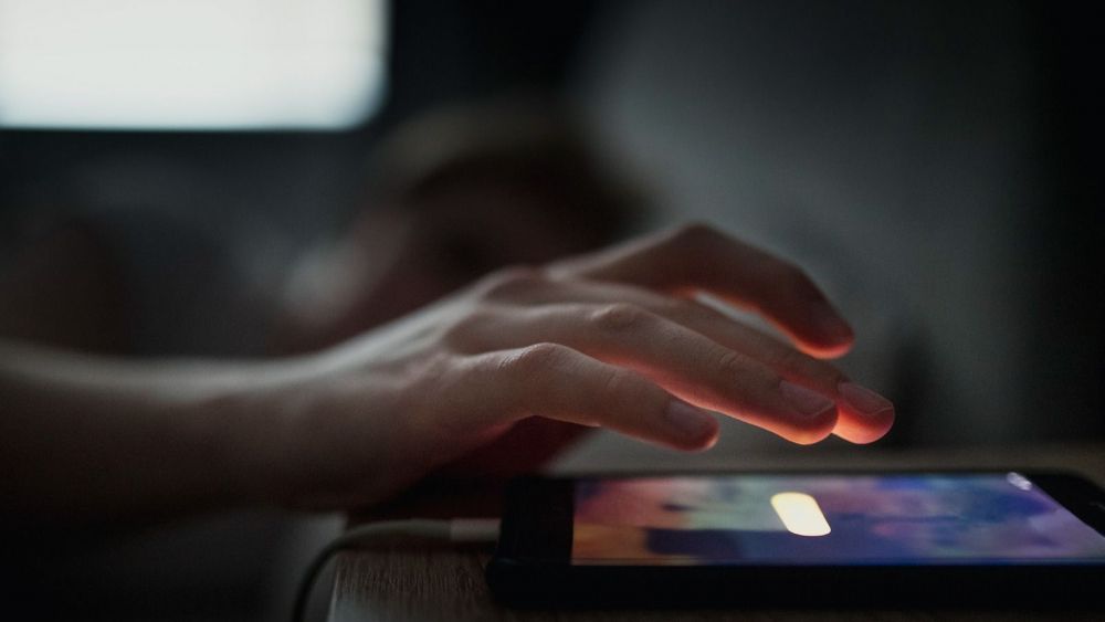 Una persona apaga l'alarma del mòbil mentres dorm Una persona apaga l'alarma del mòbil mentres dorm