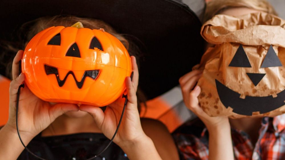 Una xiqueta i un xiquet amb una carabassa de Halloween