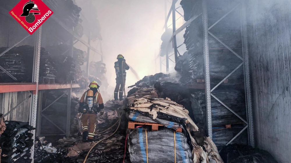 Dos bomberos trabajan en la extinción del incendio en la nave industrial de Elda Dos bomberos trabajan en la extinción del incendio en la nave industrial de Elda
