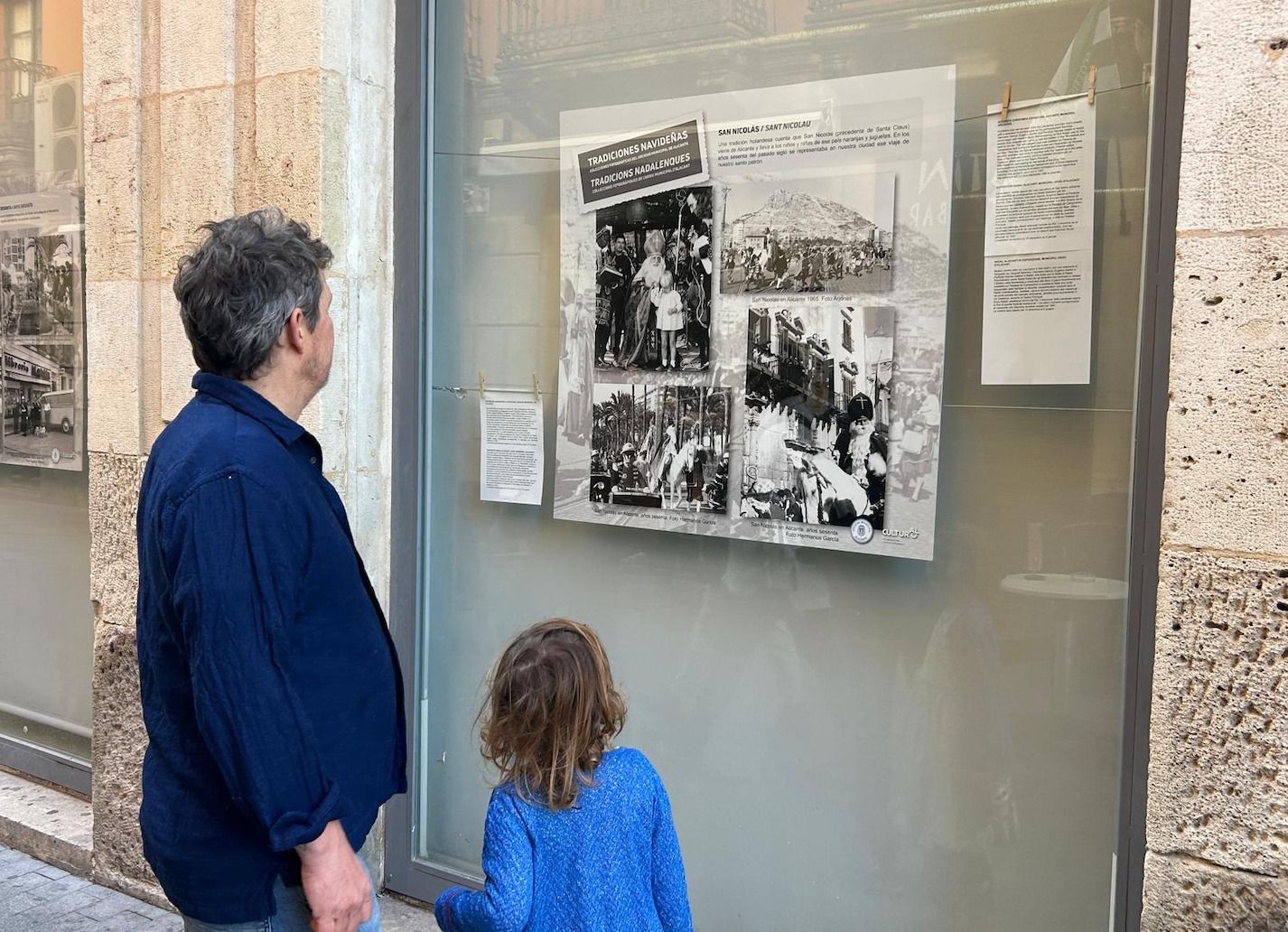 Un padre y su hija miran la exposición de la Navidad del Archivo Municipal de Alicante