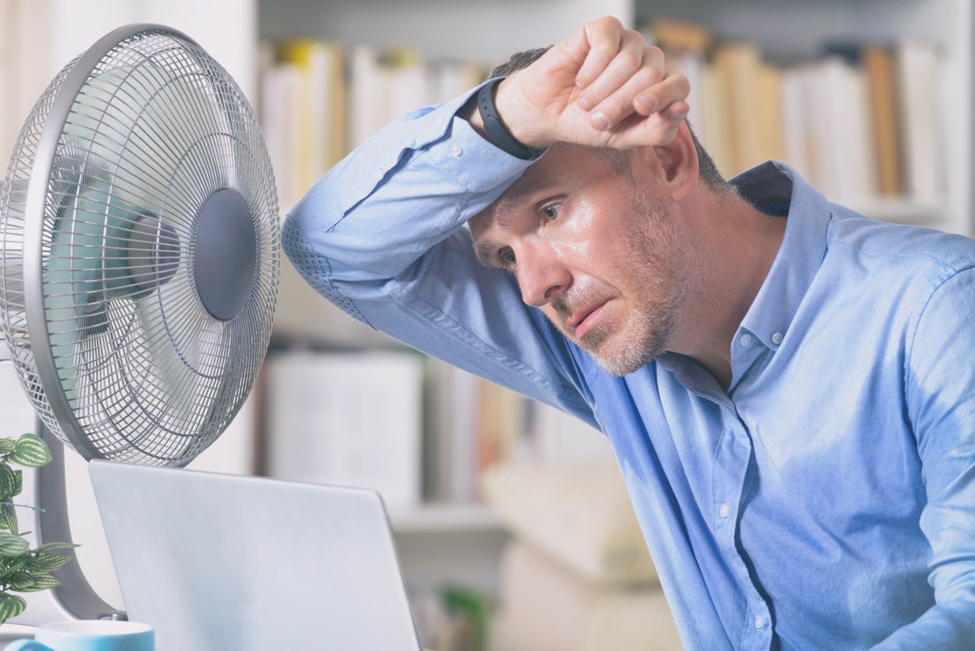 Un hombre delante de un ventilador en una ola de calor