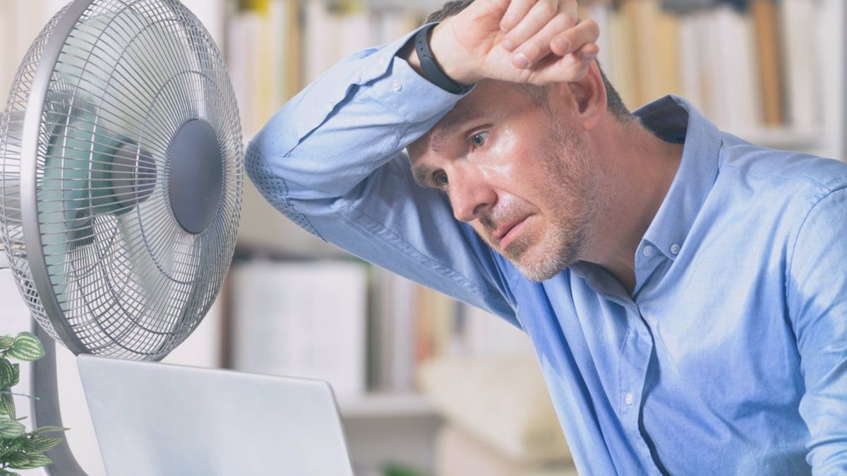 Un hombre delante de un ventilador en una ola de calor