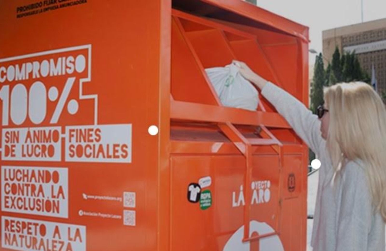 Una mujer introduce ropa en un contenedor textil en Alicante