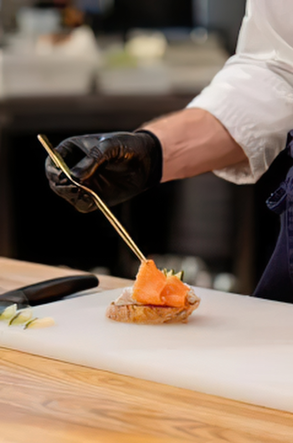 Un chef colocando sobre un trozo de pan una loncha de salmón ahumado