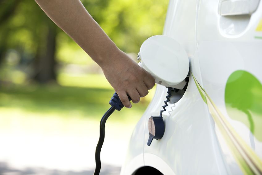 Una persona recarga un coche eléctrico Una persona recarga un coche eléctrico